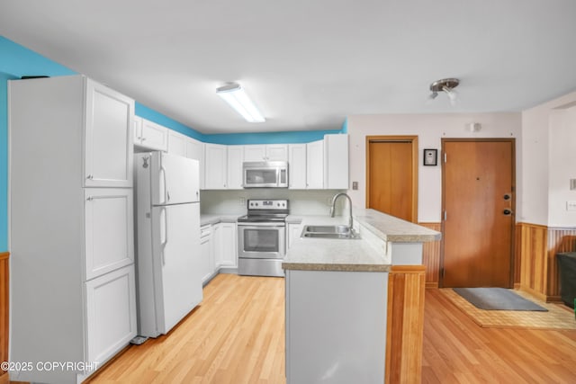 8515 Jewel Lake Rd # 25, Anchorage, AK 99502 - kitchen featuring stainless steel appliances, a peninsula, a sink, light wood-style flooring, and a wainscoted wall