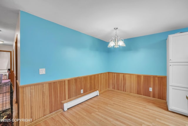 8515 Jewel Lake Rd # 25, Anchorage, AK 99502 - spare room featuring a baseboard radiator, a wainscoted wall, a chandelier, wood finished floors, and wooden walls