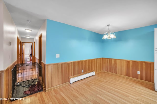 8515 Jewel Lake Rd # 25, Anchorage, AK 99502 - spare room with baseboard heating, a wainscoted wall, wood finished floors, a chandelier, and wooden walls