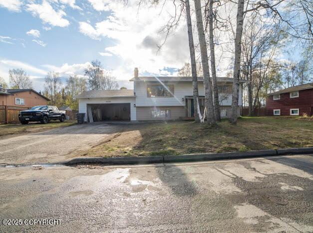 split foyer home with driveway, a garage, and a chimney
