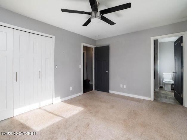 unfurnished bedroom with light carpet, a closet, baseboards, and connected bathroom