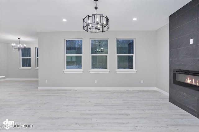 unfurnished living room with a chandelier, light wood-style floors, a fireplace, baseboards, and recessed lighting
