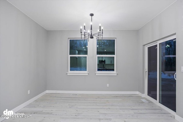 unfurnished dining area with a chandelier, wood finished floors, and baseboards