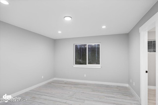 empty room featuring light wood finished floors, baseboards, and recessed lighting