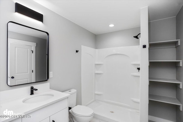 bathroom with a stall shower, toilet, and vanity