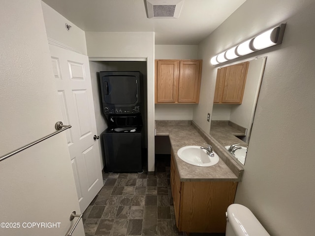 123 E 24th Ave # 4, Anchorage, AK 99503 - bathroom featuring stacked washing machine and dryer, vanity, and stone finish floors