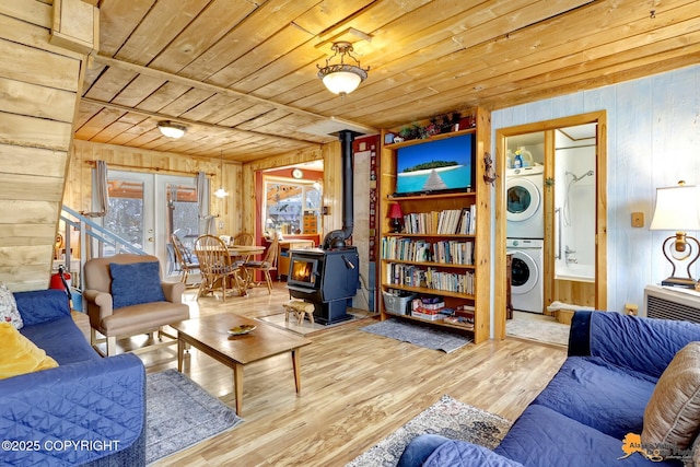 13706 E First St, Talkeetna, AK 99676 - living area with a wood stove, stacked washing machine and dryer, wood walls, wooden ceiling, and wood finished floors