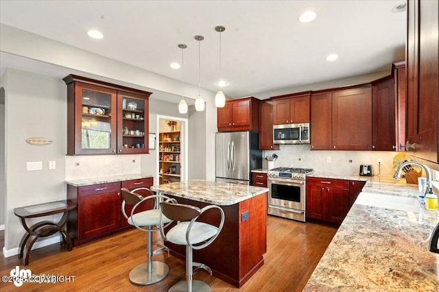 18627 Mountain Plover Cir, Anchorage, AK 99516 - kitchen with stainless steel appliances, wood finished floors, a kitchen island, glass insert cabinets, and backsplash