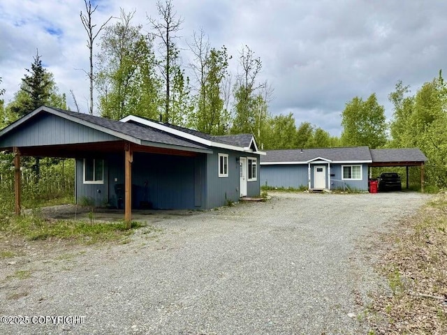 3745 E Tambert Dr, Wasilla, AK 99654 - view of front facade with gravel driveway, a carport, an outbuilding, and a shingled roof