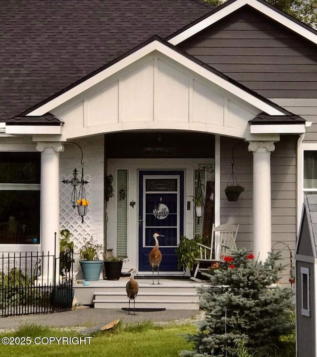 doorway to property featuring roof with shingles and covered porch
