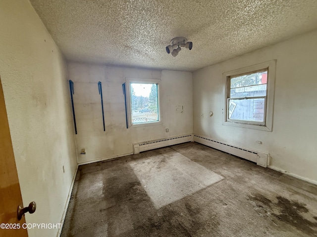 spare room with baseboard heating, healthy amount of natural light, a textured ceiling, and baseboards