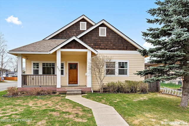 view of front of property with a porch, a front lawn, and roof with shingles