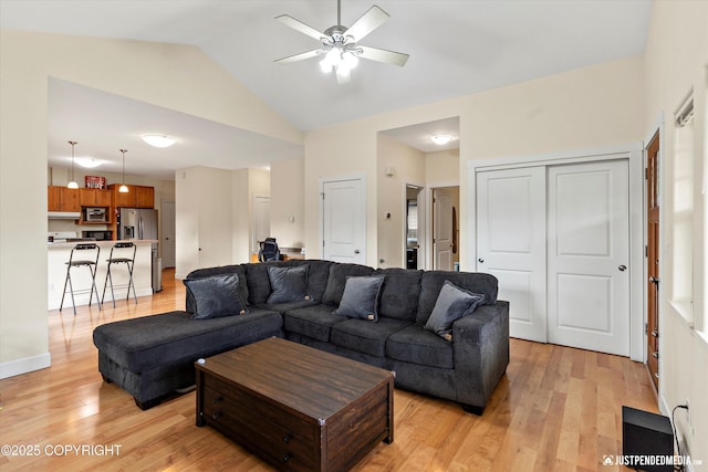 living area featuring light wood-style floors, ceiling fan, and vaulted ceiling