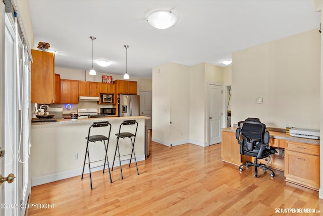 kitchen featuring stainless steel fridge, a desk, light wood finished floors, under cabinet range hood, and white range with gas cooktop
