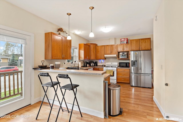 kitchen featuring stainless steel refrigerator with ice dispenser, white range with gas cooktop, black microwave, a peninsula, and light wood finished floors