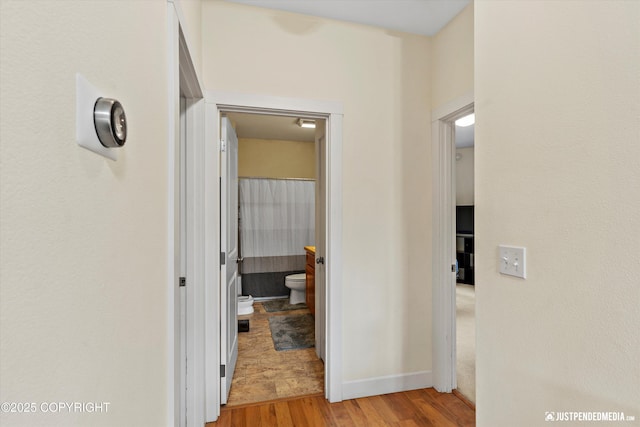 hallway with light wood-type flooring and baseboards