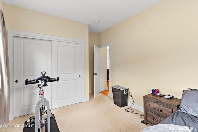 bedroom featuring light colored carpet, baseboards, and a closet