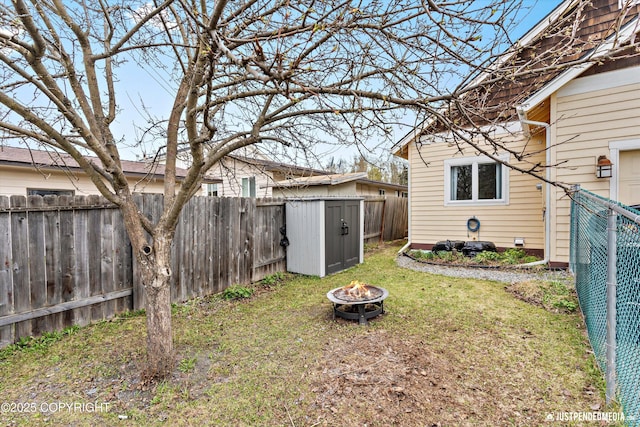 view of yard featuring an outdoor fire pit, a storage unit, and an outbuilding