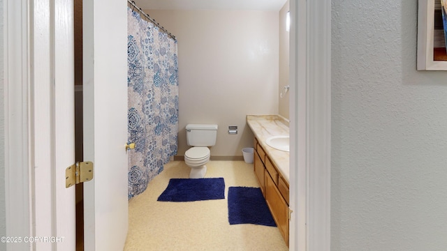 bathroom with a textured wall, toilet, vanity, and a shower with curtain