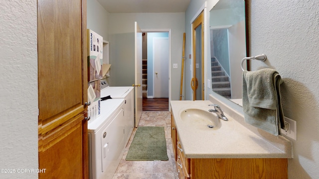 bathroom featuring washing machine and clothes dryer, vanity, and a textured wall