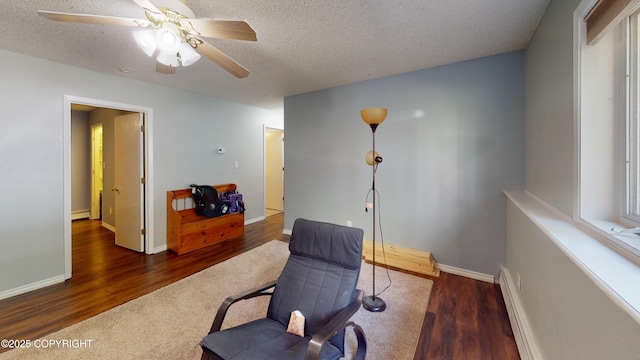 living area featuring a baseboard heating unit, a textured ceiling, and wood finished floors