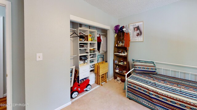 carpeted bedroom featuring baseboards, a closet, and a textured ceiling