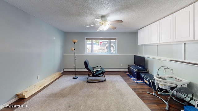sitting room featuring a textured ceiling, ceiling fan, dark wood-style flooring, baseboard heating, and baseboards