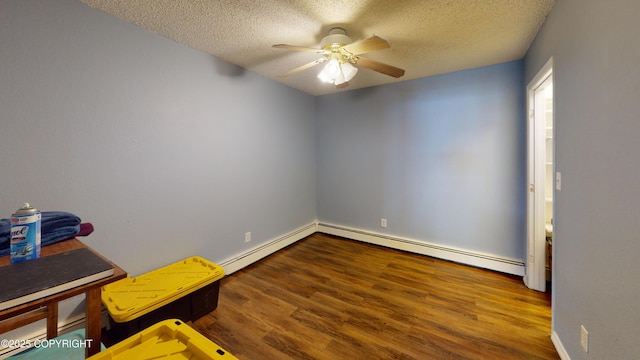 spare room featuring baseboard heating, a textured ceiling, wood finished floors, and a ceiling fan