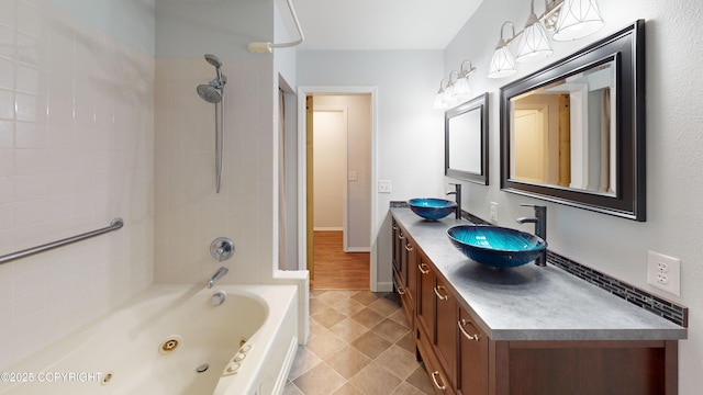 bathroom featuring a combined bath / shower with jetted tub, tile patterned floors, double vanity, and a sink