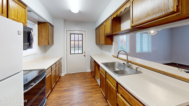 kitchen with wood finished floors, a sink, freestanding refrigerator, range with two ovens, and light countertops