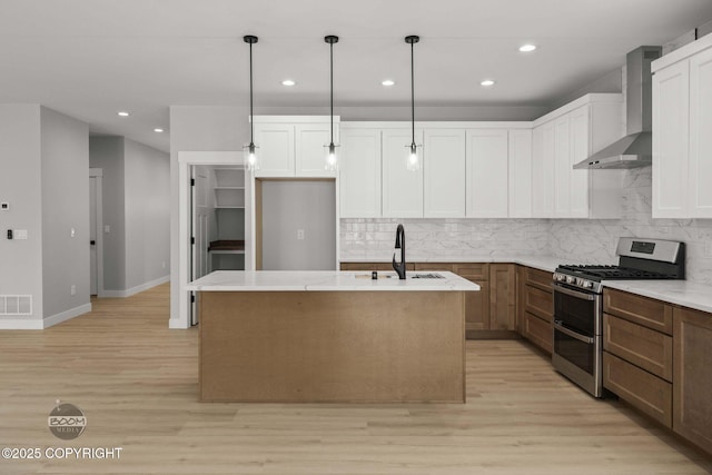 kitchen with range with two ovens, wall chimney range hood, a sink, recessed lighting, and light wood-type flooring