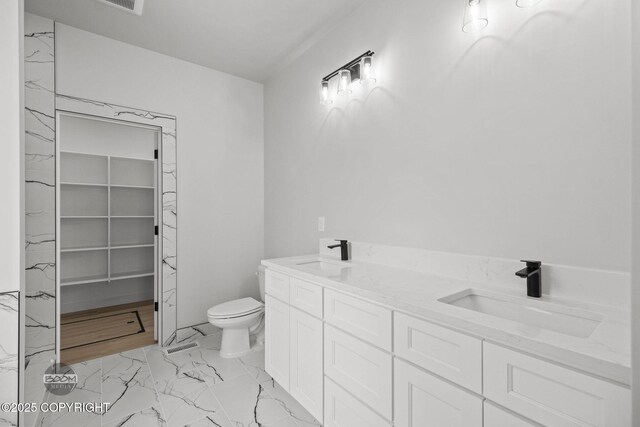 full bathroom with toilet, marble look tile flooring, and double vanity