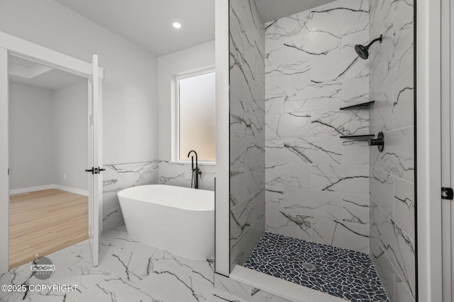 bathroom with a marble finish shower, marble look tiles, a freestanding tub, recessed lighting, and tile walls