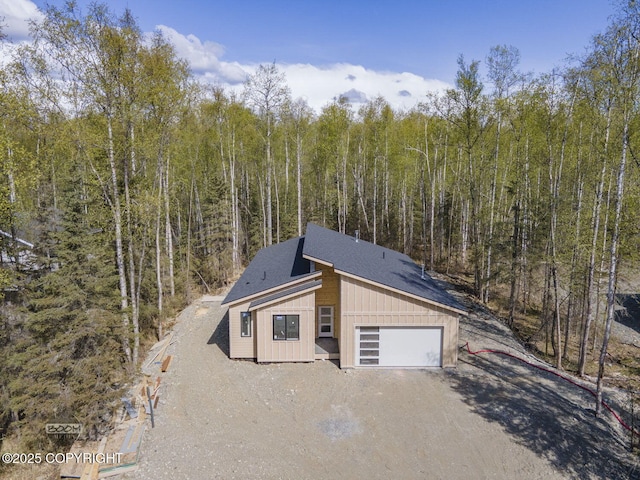 garage featuring a view of trees and driveway