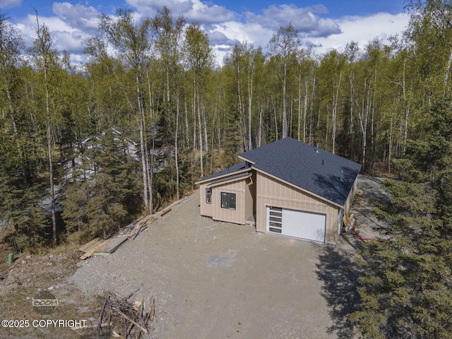 view of side of home with driveway, a wooded view, and board and batten siding