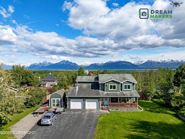 6701 W Leopold Loop, Wasilla, AK 99654 - traditional-style home with covered porch, asphalt driveway, a mountain view, a front yard, and a garage