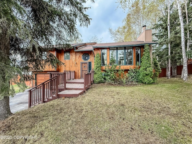 view of front of property with a front yard, a chimney, a garage, and driveway