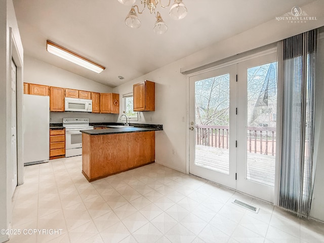 kitchen with white appliances, lofted ceiling, a peninsula, light flooring, and dark countertops