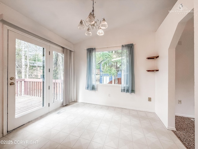 unfurnished dining area featuring vaulted ceiling, a chandelier, arched walkways, and baseboards