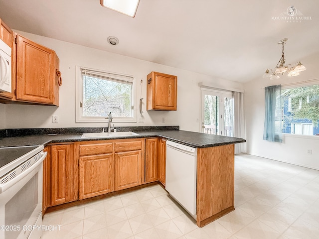 kitchen featuring white appliances, a sink, a peninsula, plenty of natural light, and vaulted ceiling
