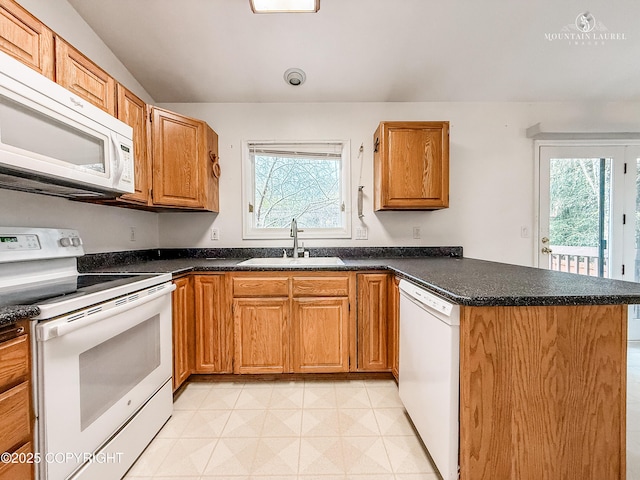 kitchen with white appliances, a sink, a peninsula, and plenty of natural light