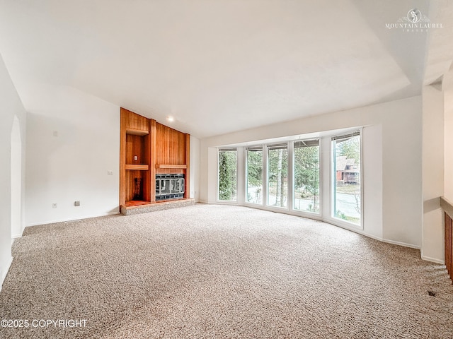 unfurnished living room with vaulted ceiling, carpet flooring, a fireplace, and baseboards