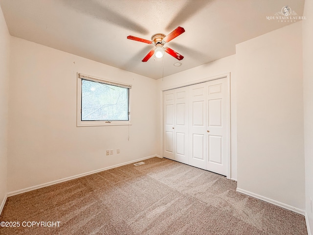 unfurnished bedroom with carpet floors, a closet, baseboards, and ceiling fan