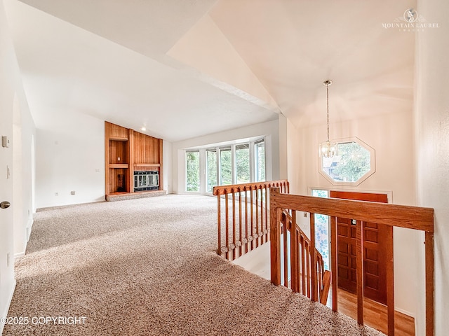 hallway with an upstairs landing, vaulted ceiling, light carpet, a chandelier, and baseboards
