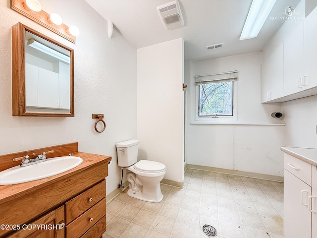 bathroom featuring vanity, baseboards, toilet, and a shower