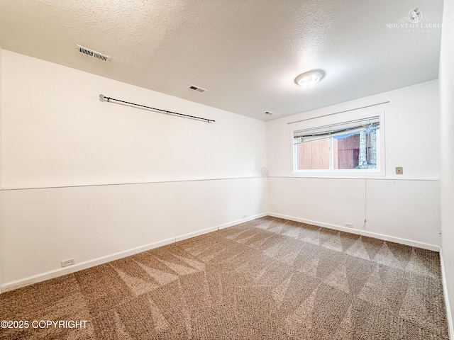 spare room featuring baseboards, a textured ceiling, and carpet floors