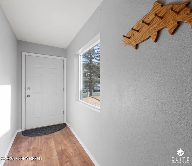 doorway featuring light wood finished floors and baseboards