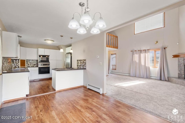 kitchen featuring a sink, dark countertops, white cabinets, black appliances, and a baseboard radiator