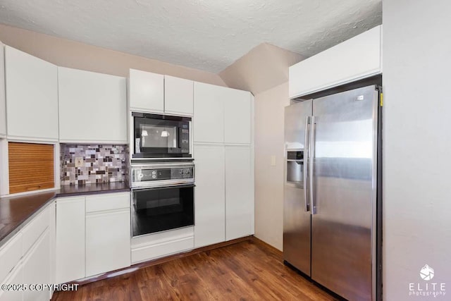 kitchen with black appliances, dark wood finished floors, backsplash, white cabinets, and dark countertops