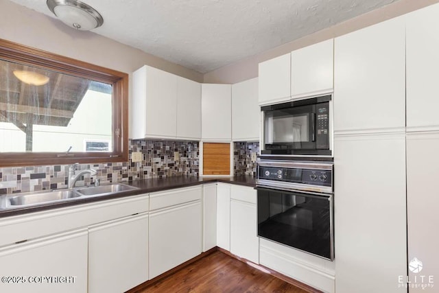 kitchen featuring white cabinets, tasteful backsplash, black appliances, and a sink
